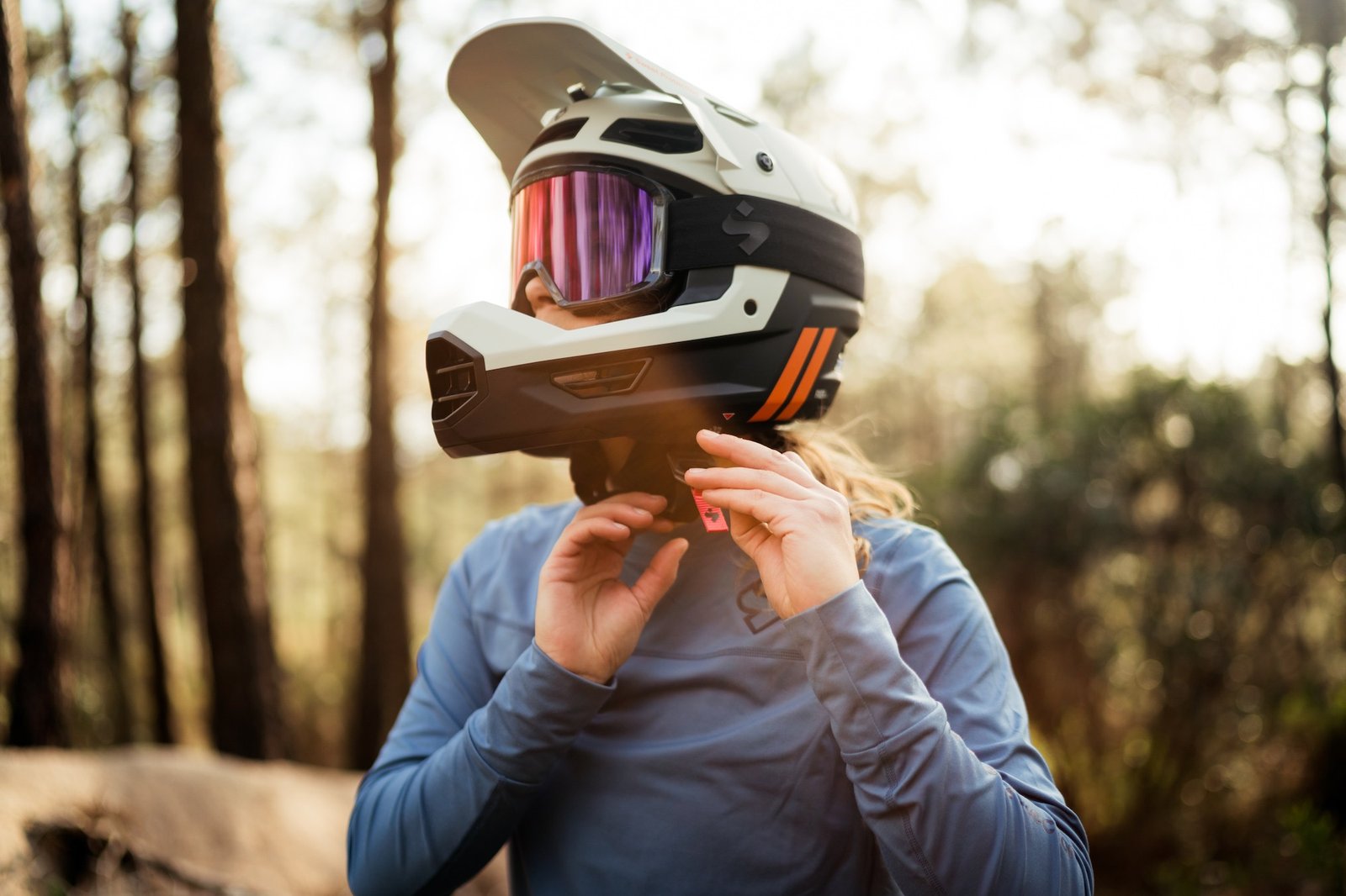 a female mountain biker putting on the Fixer Composite 2Vi MIPS helmet