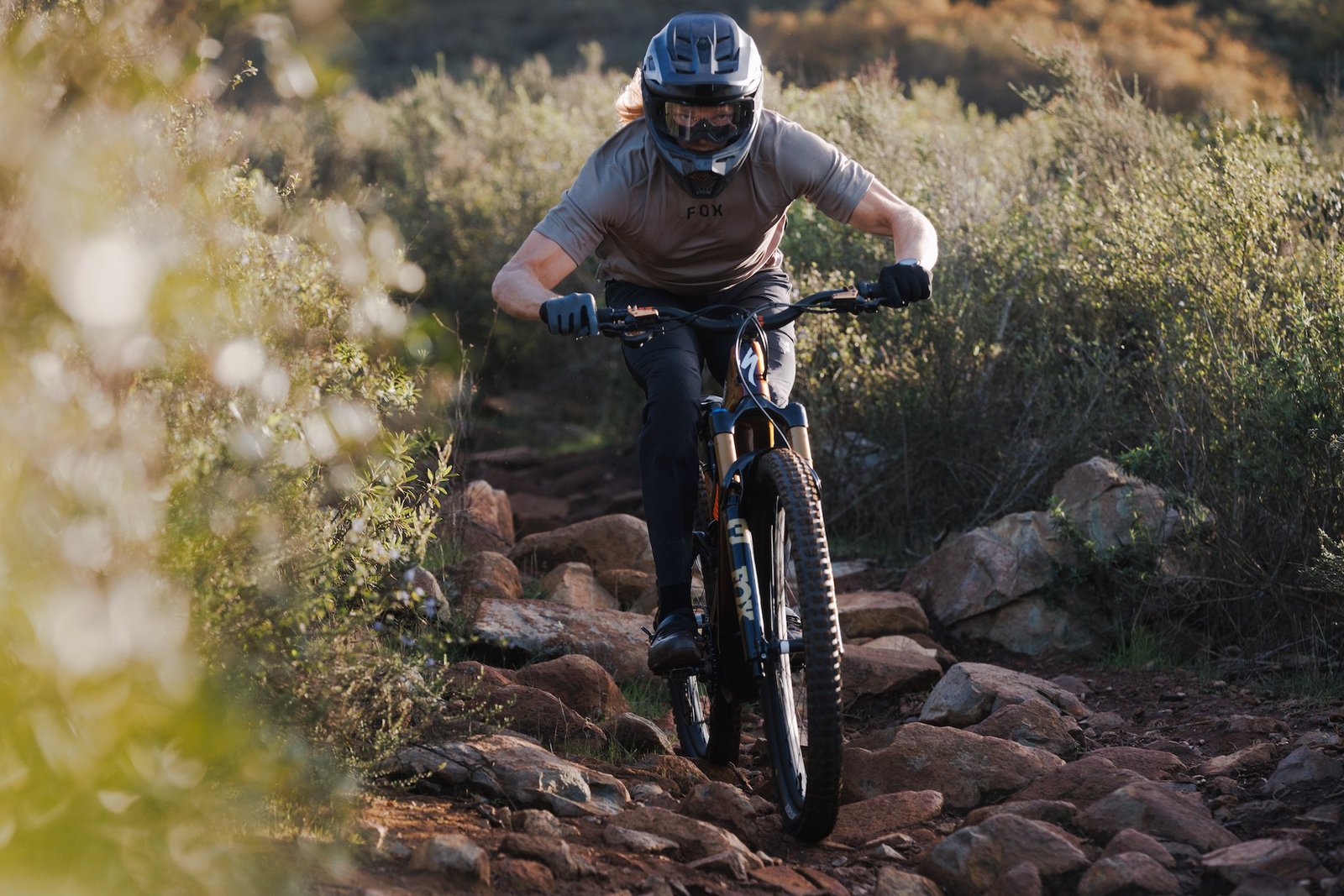 Cody Kelly riding down a chunky trail on the new Fox 38
