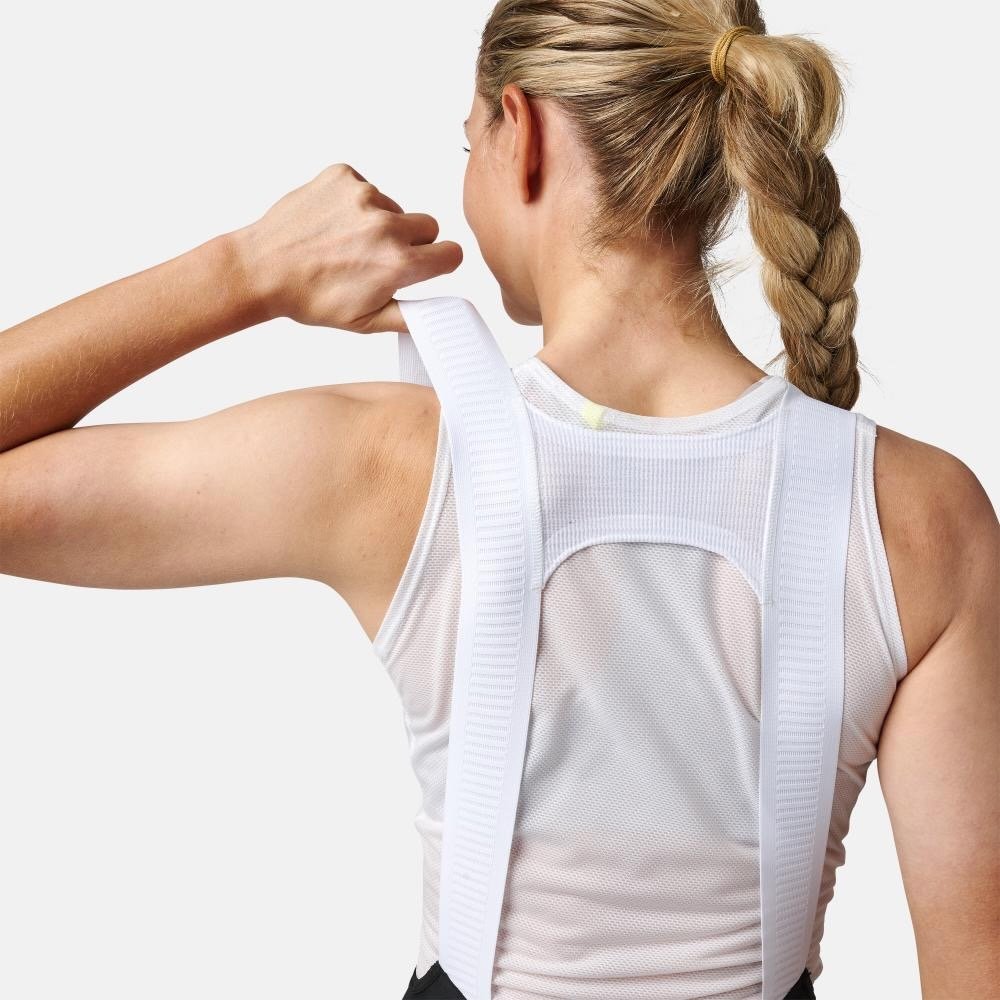 studio image of a woman wearing the pearl izumi red bibs and pulling up on the strap