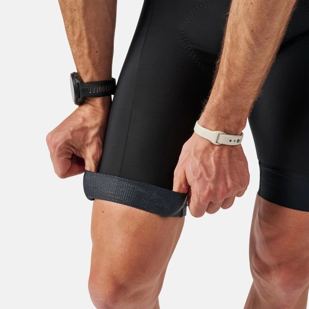 studio image of a man wearing the Pearl Izumi Red Bibs and showing the leg grippers