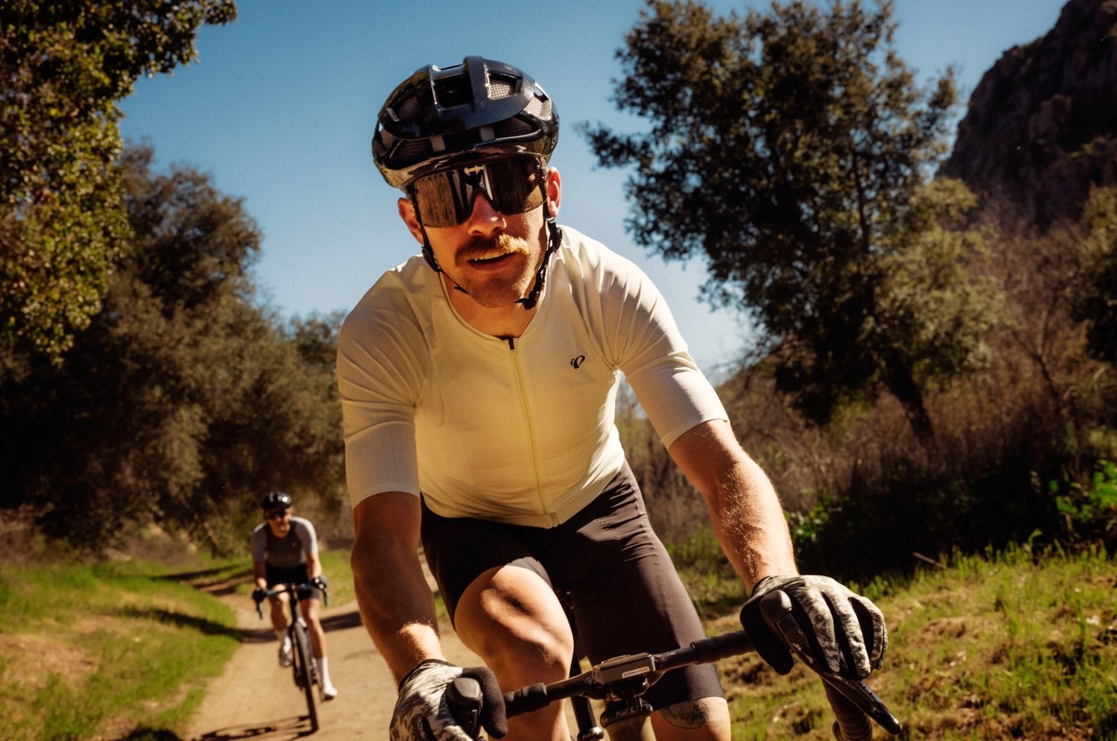 a couple riding on a gravel road while wearing the Pearl Izumi Red jerseys and bibs.