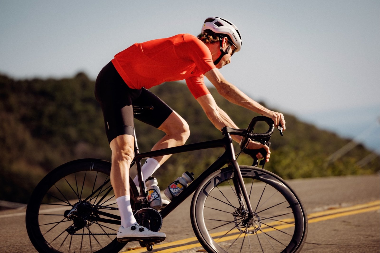 a man riding a road bike while wearing the pearl izumi red jersey and bibs