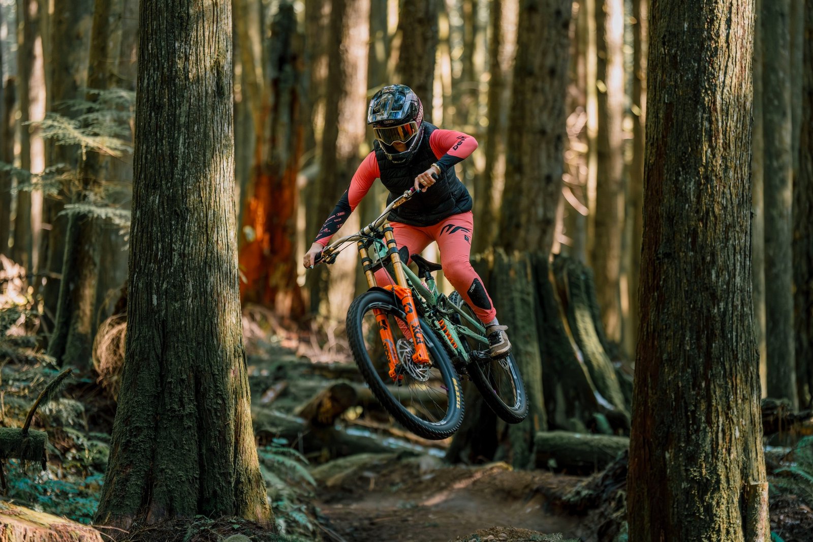 a rider on a downhill mountain bike hitting a jump while riding with the Race Face Atlas handlebar.