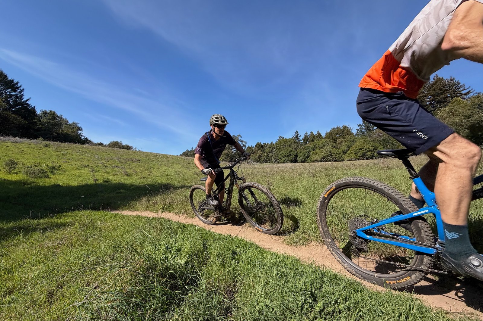 Scot Nicol chasing Colin Hughes down trail through and open meadow. 