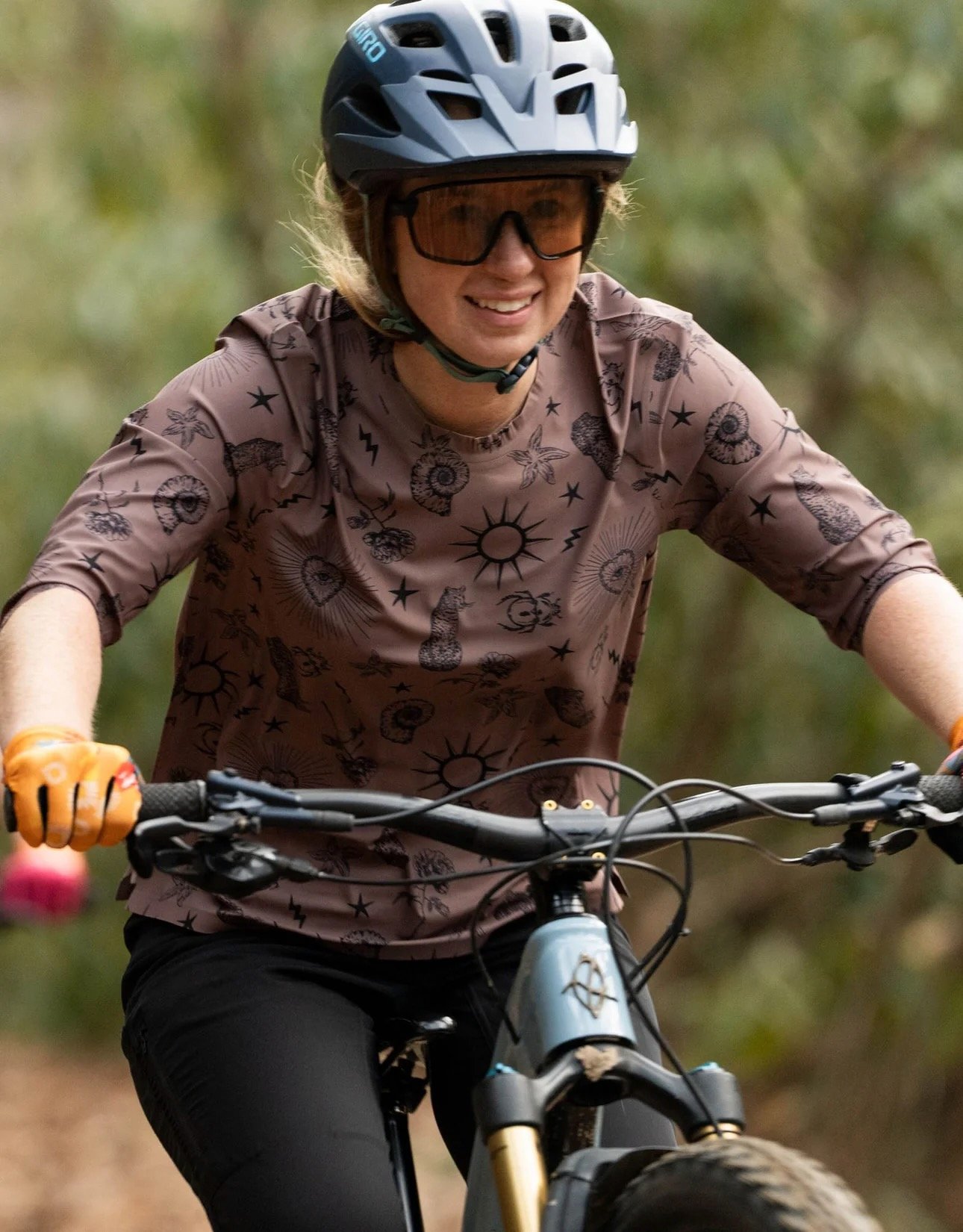 a female rider riding toward the cmaer with the new Ink pattern shirt on