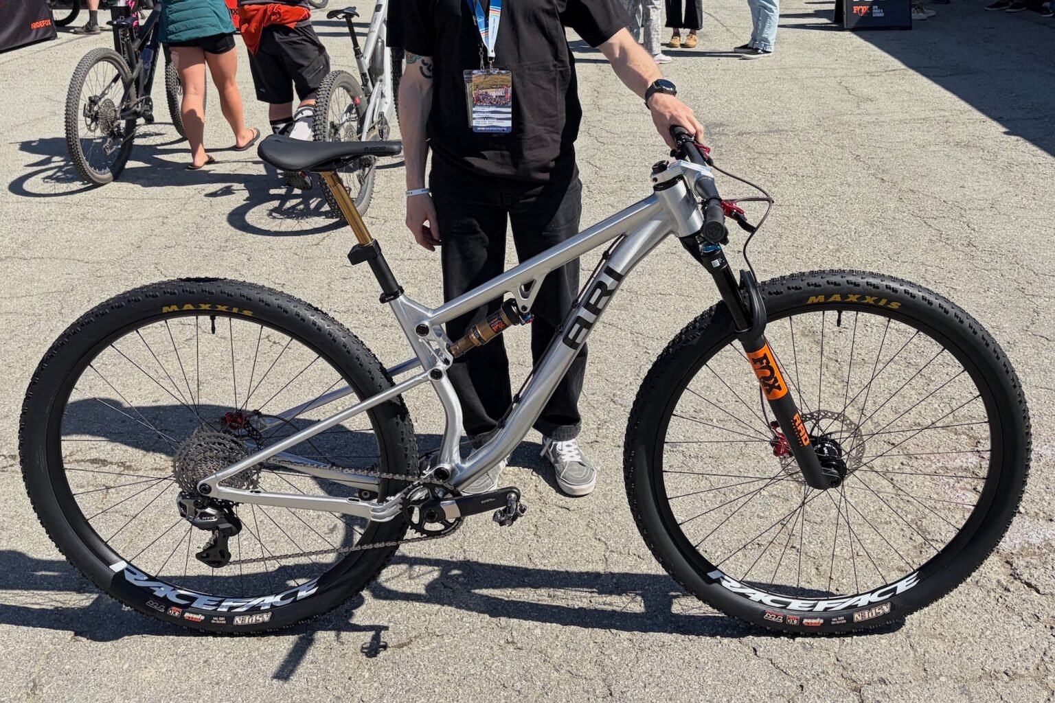 a person holding the Ari full suspesnion 32" prototype bike at Sea Otter
