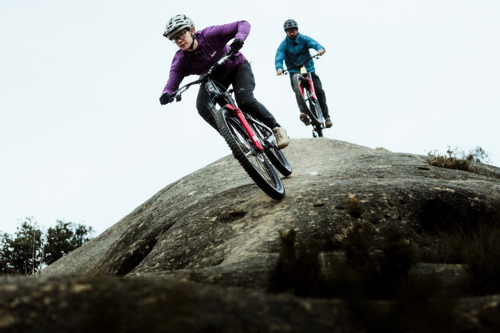 Two riders on Bad Habit bikes riding down a rock slab