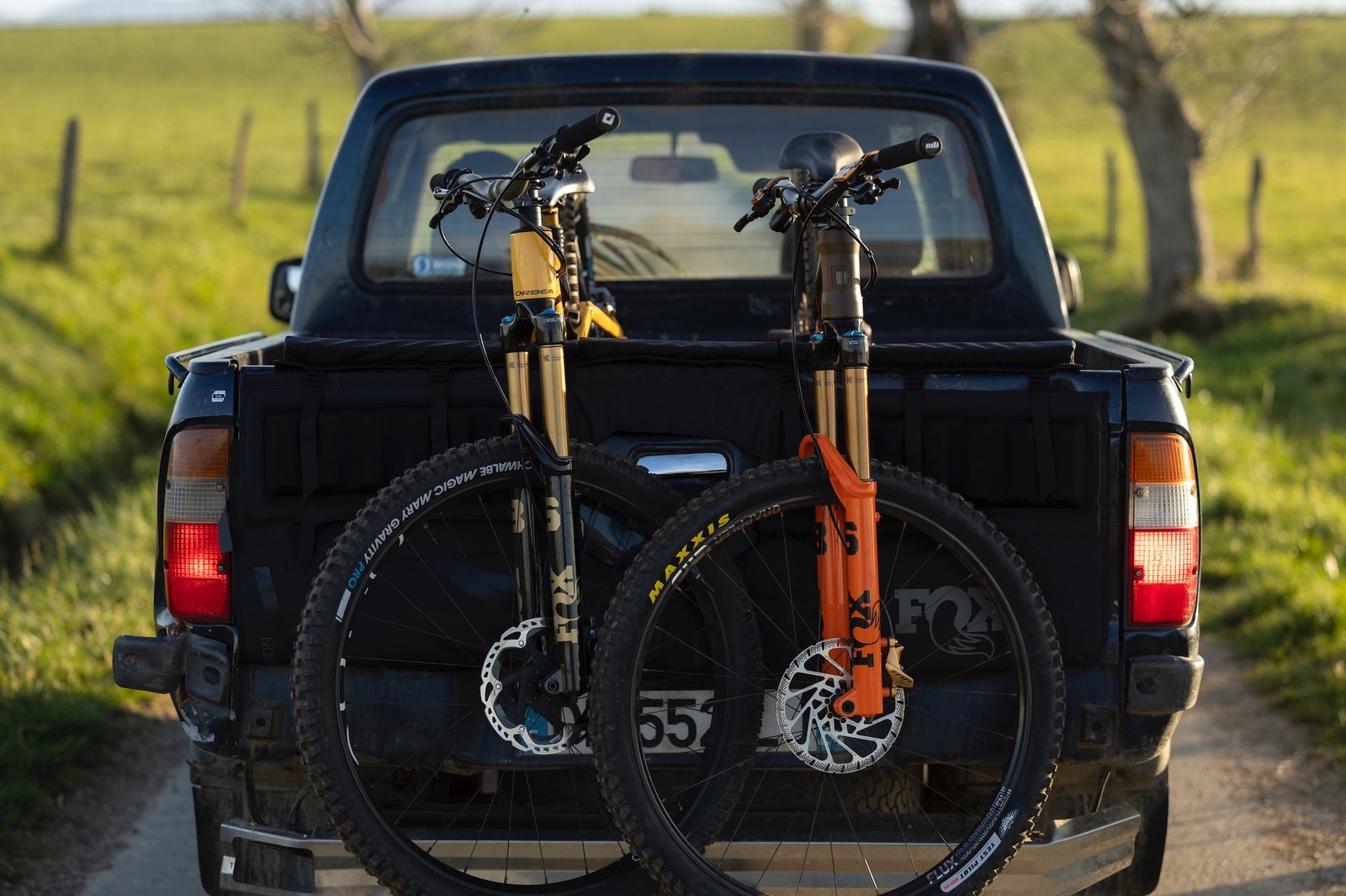 two bikes with new Fox 36 forks hanging off the tailgate of a pickup truck.