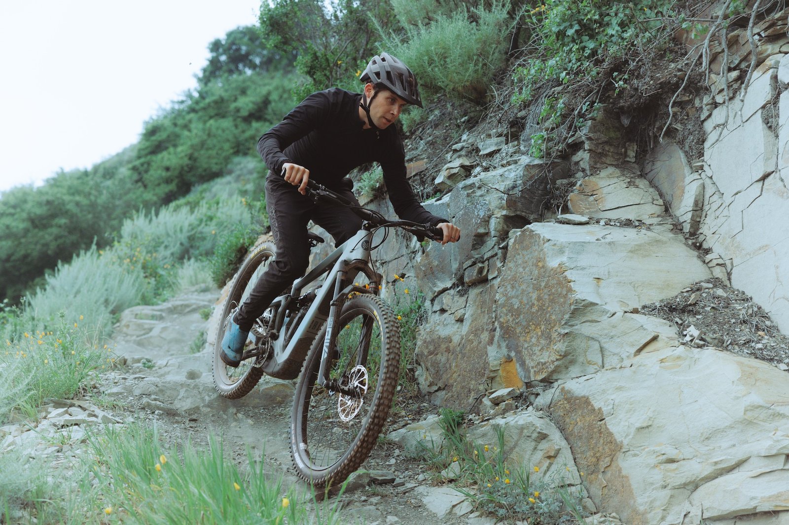 a rider on the Ibis Oso S riding past a steep rock wall.