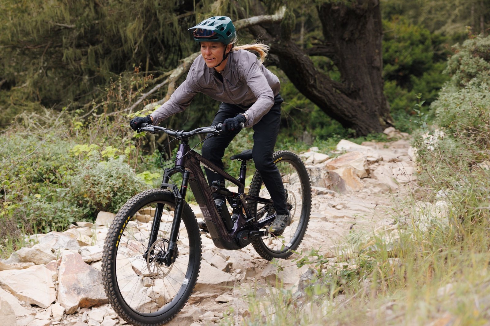 a woman riding the Ibis Oso TR down a rocky trail.