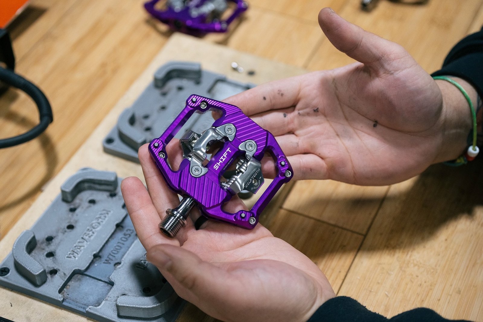 a person holding the Wolf Tooth SHIFT pedals in their hand.
