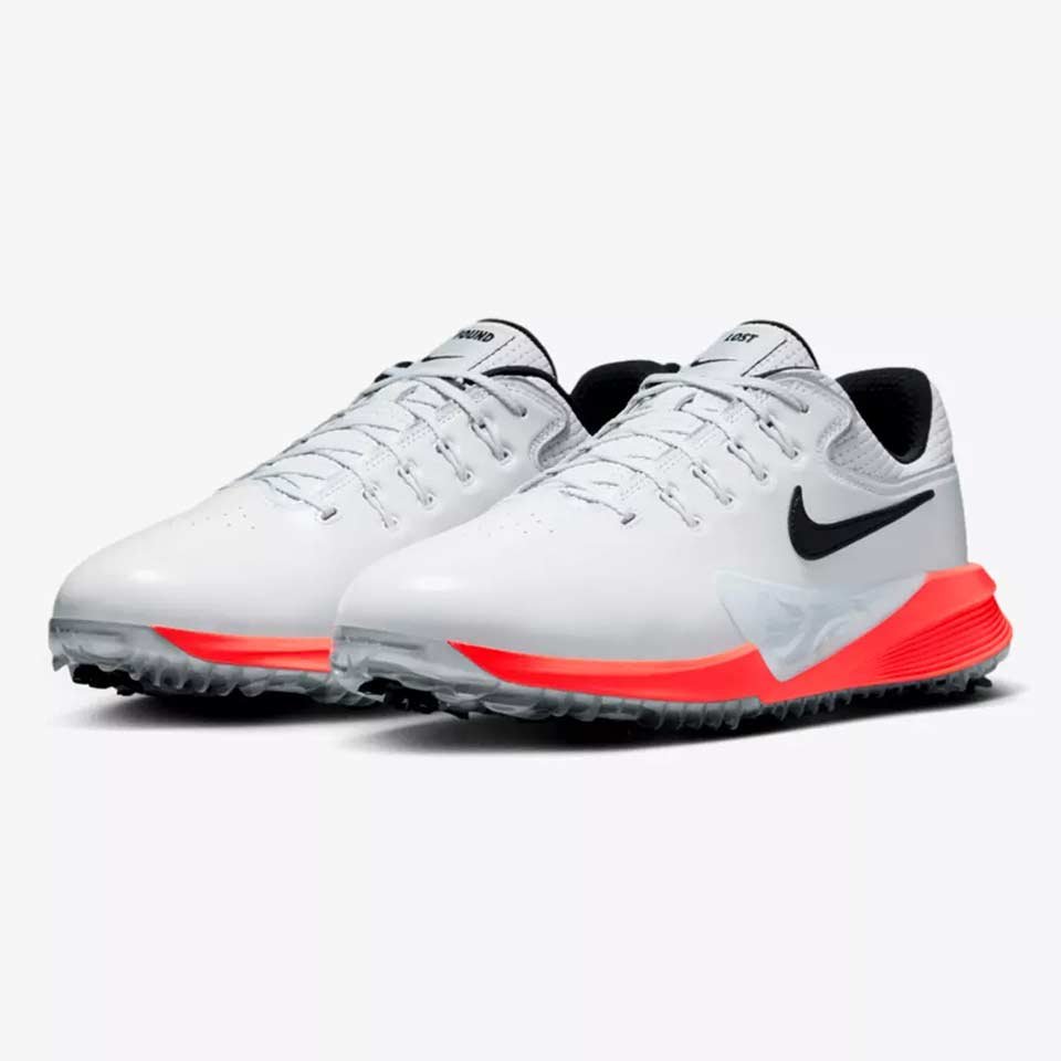 A pair of white Nike golf shoes, inspired by Scottie Scheffler, with black swooshes, black inner lining, and bright red accents on the midsole and outsole, displayed on a plain light background.